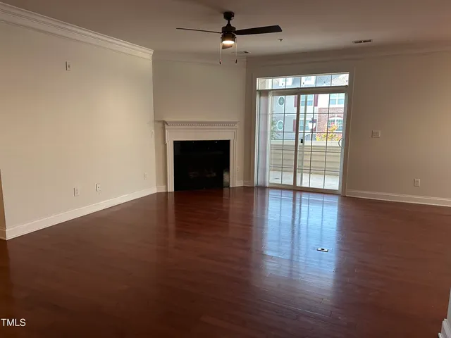 an empty room with wooden floor fireplace and windows