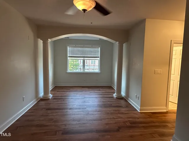 an empty room with wooden floor cabinet and windows