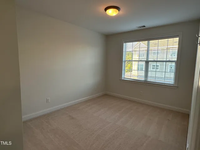 an empty room with wooden floor fireplace and windows