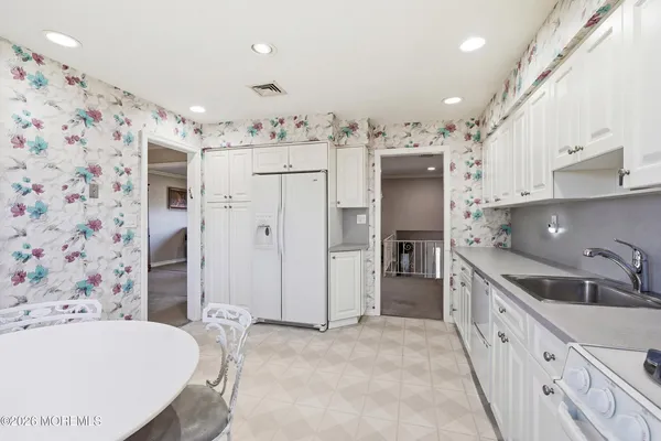 a large white kitchen with a sink and refrigerator
