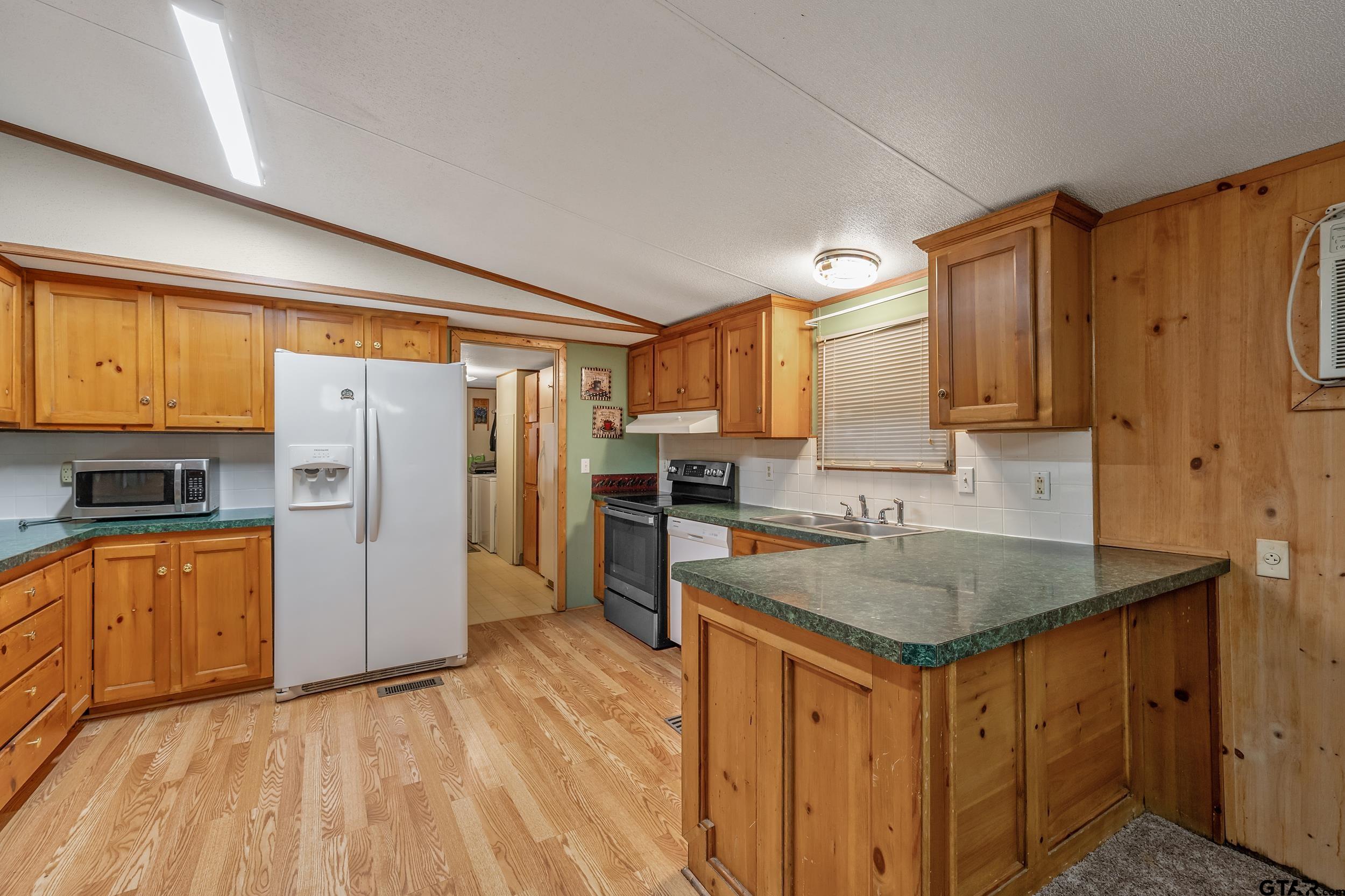 220 Broken Bow Quitman, TX 75783 - Photo 8 of 28 a kitchen with stainless steel appliances granite countertop a refrigerator a sink dishwasher and wooden cabinets with wooden floor