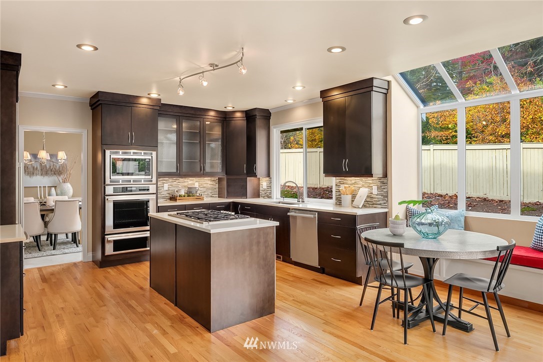 3013 213th Street Southeast Bothell, WA 98021 - Photo 10 of 25 a kitchen with stainless steel appliances granite countertop a stove top oven a sink dishwasher a dining table and chairs with wooden floor