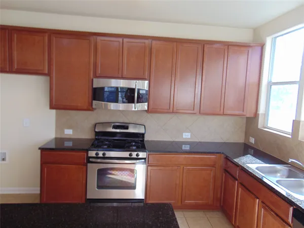 a kitchen with granite countertop wood cabinets and stainless steel appliances