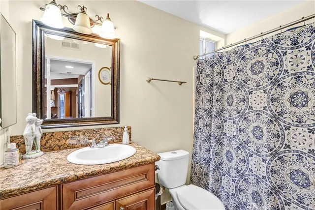 a bathroom with a granite countertop toilet sink and mirror