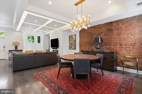 a living room with stainless steel appliances lots of furniture and a refrigerator