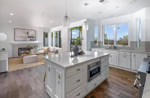 a kitchen with stainless steel appliances granite countertop a stove a sink dishwasher a refrigerator and a fireplace with wooden floor