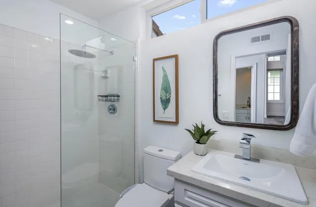 a bathroom with a toilet a sink a shower and a mirror