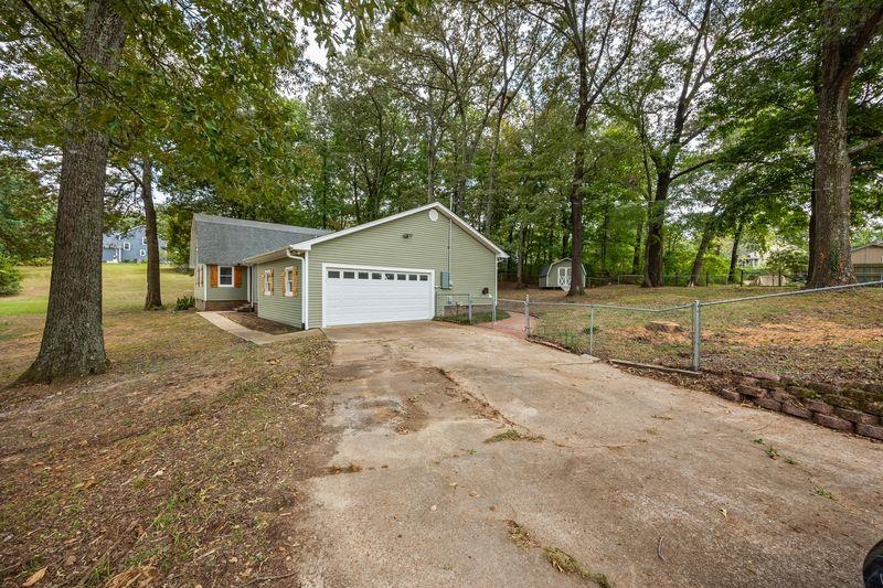 80 Pinewood Drive Jackson, TN 38305 - Photo 2 of 27 View of home's exterior featuring driveway, view of wooded area, a shed, and a garage