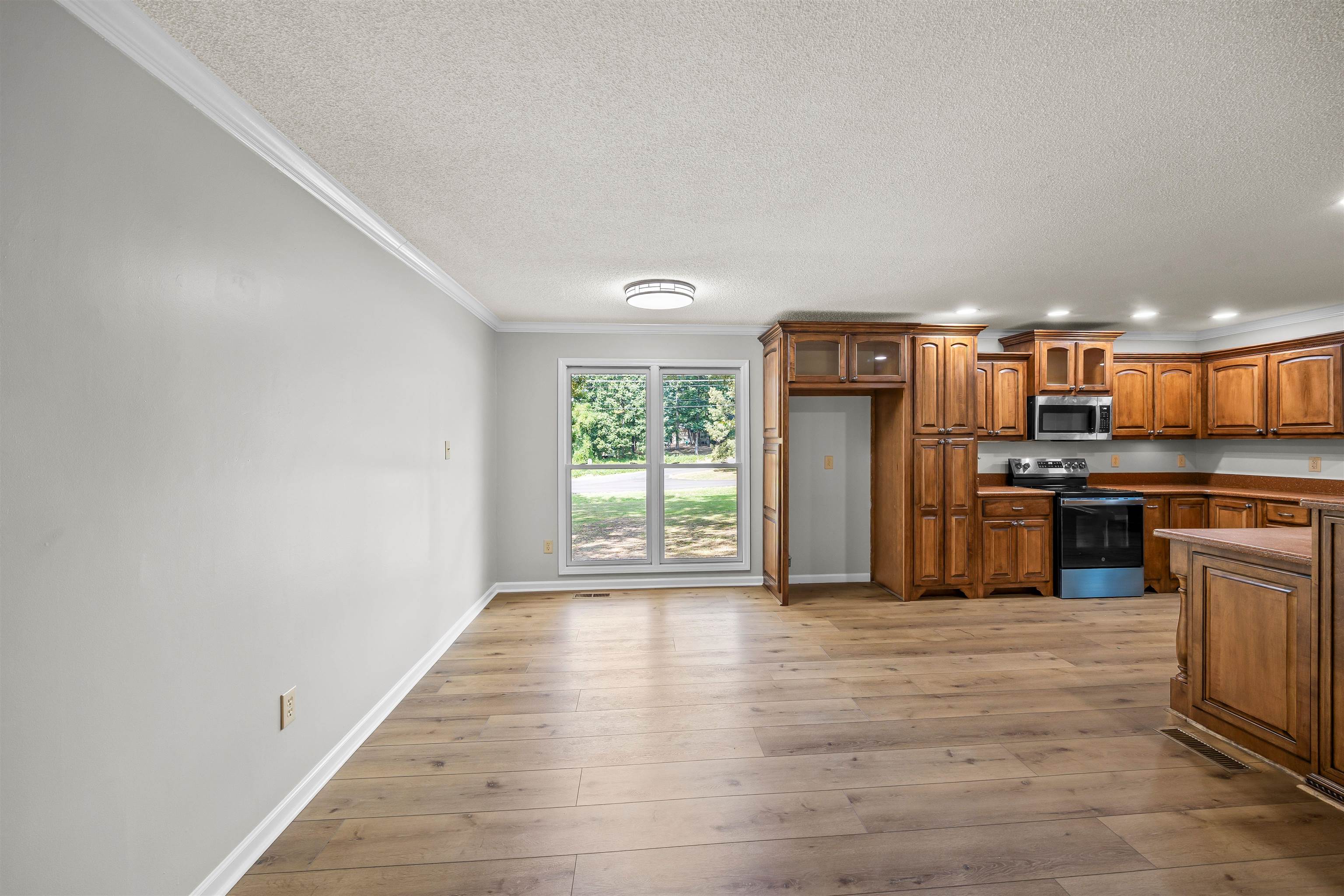 80 Pinewood Drive Jackson, TN 38305 - Photo 4 of 27 Kitchen featuring brown cabinetry, ornamental molding, appliances with stainless steel finishes, light wood-style floors, and a textured ceiling