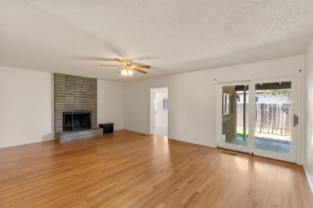 an empty room with wooden floor fireplace and windows
