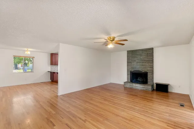 a view of an empty room with wooden floor and a fireplace