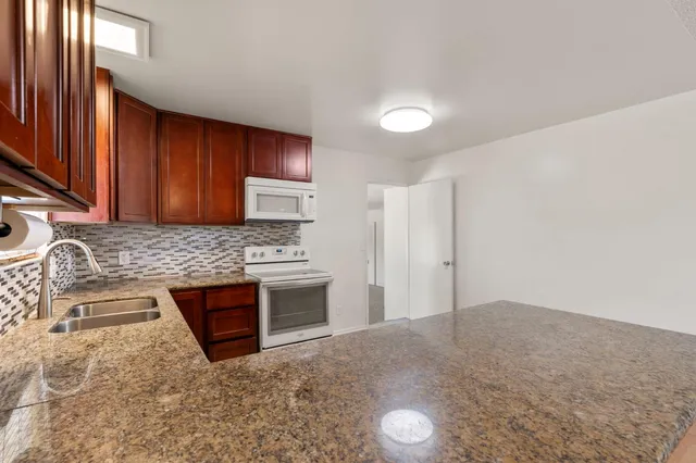 a kitchen with granite countertop a stove top oven sink and cabinets