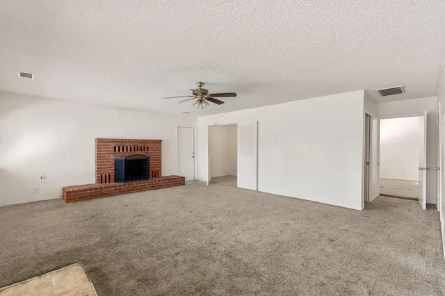 an empty room with a fireplace and a chandelier fan