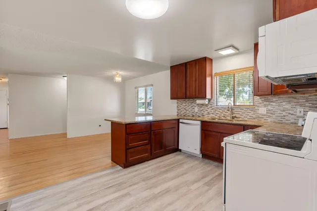 a kitchen with stainless steel appliances granite countertop a sink stove and wooden floor