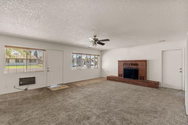 an empty room with windows and fireplace