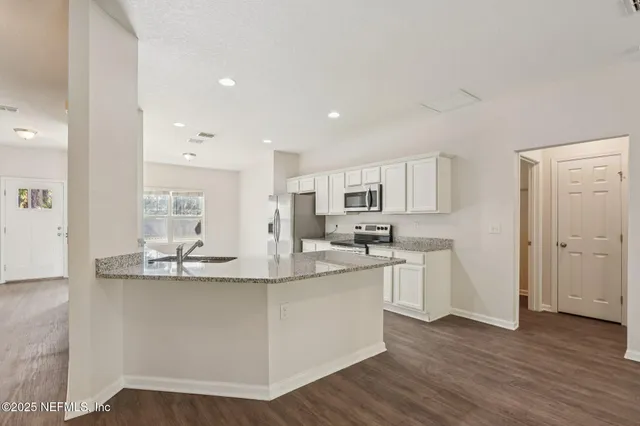 a kitchen with kitchen island white cabinets and stainless steel appliances