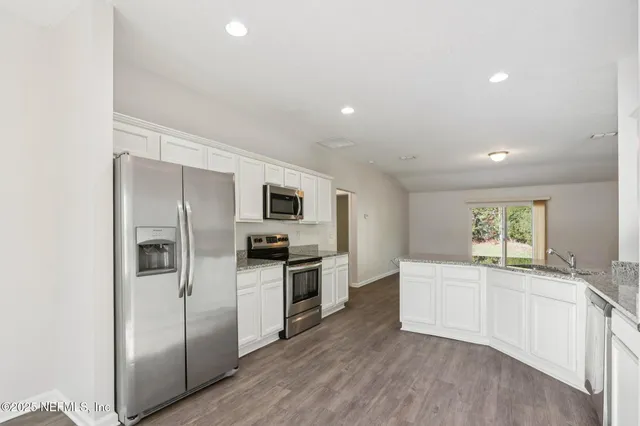 a large kitchen with a refrigerator a sink a stove and cabinets