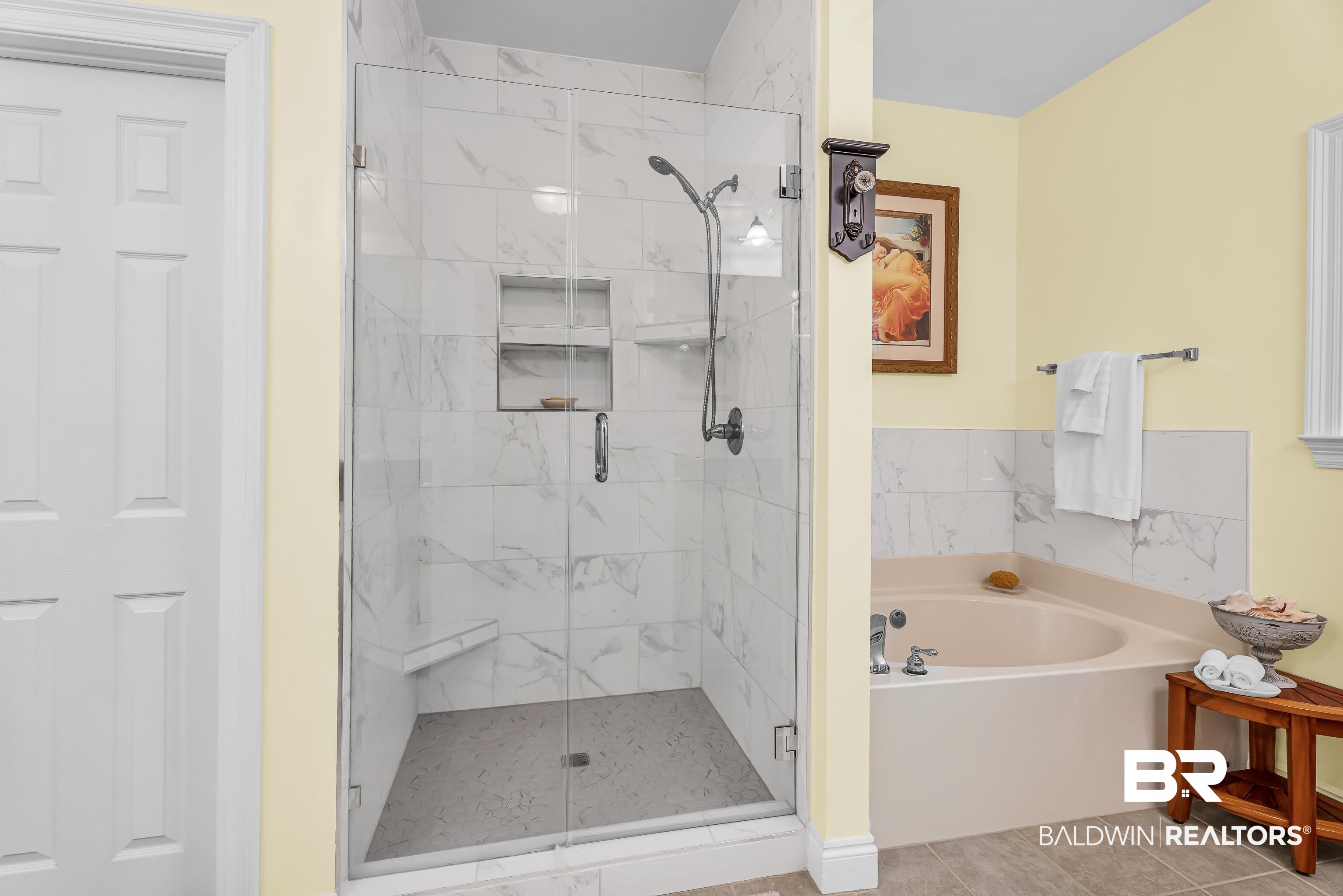 7014 Blakeley Road Daphne, AL 36527 - Photo 36 of 45 Walk-in shower featuring a glass enclosure, white marble-look wall tile, dual recessed shelves, and an integrated bench seat