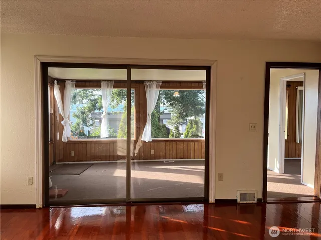 a view of empty room with wooden floor and fan