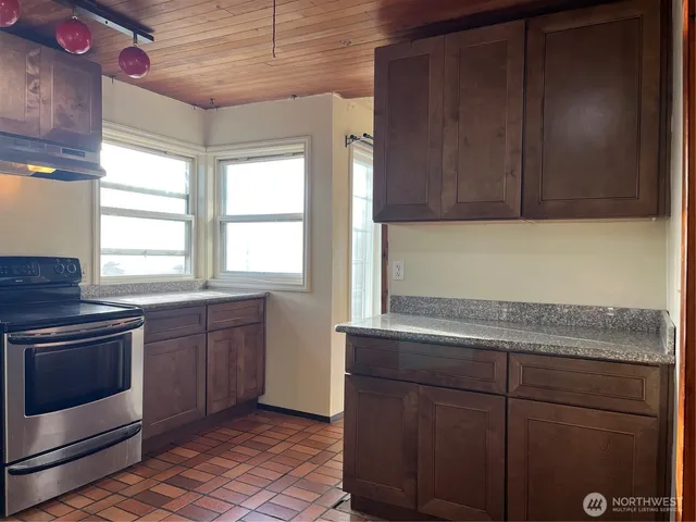 a kitchen with granite countertop cabinets stainless steel appliances and a window