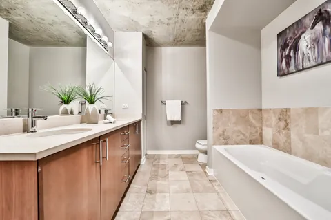 a bathroom with a double vanity sink a mirror and a bathtub