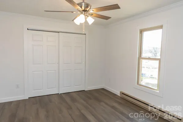 an empty room with wooden floor fan and windows