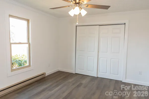 an empty room with wooden floor fan and windows
