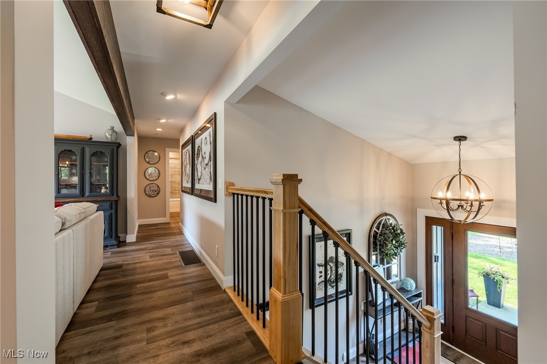 6268 Summers Road Windsor, OH 44099 - Photo 13 of 49 Hallway featuring dark wood finished floors, a chandelier, lofted ceiling, baseboards, and stairway