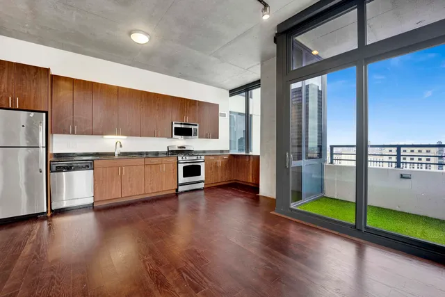 a kitchen with stainless steel appliances wooden floors and white cabinets