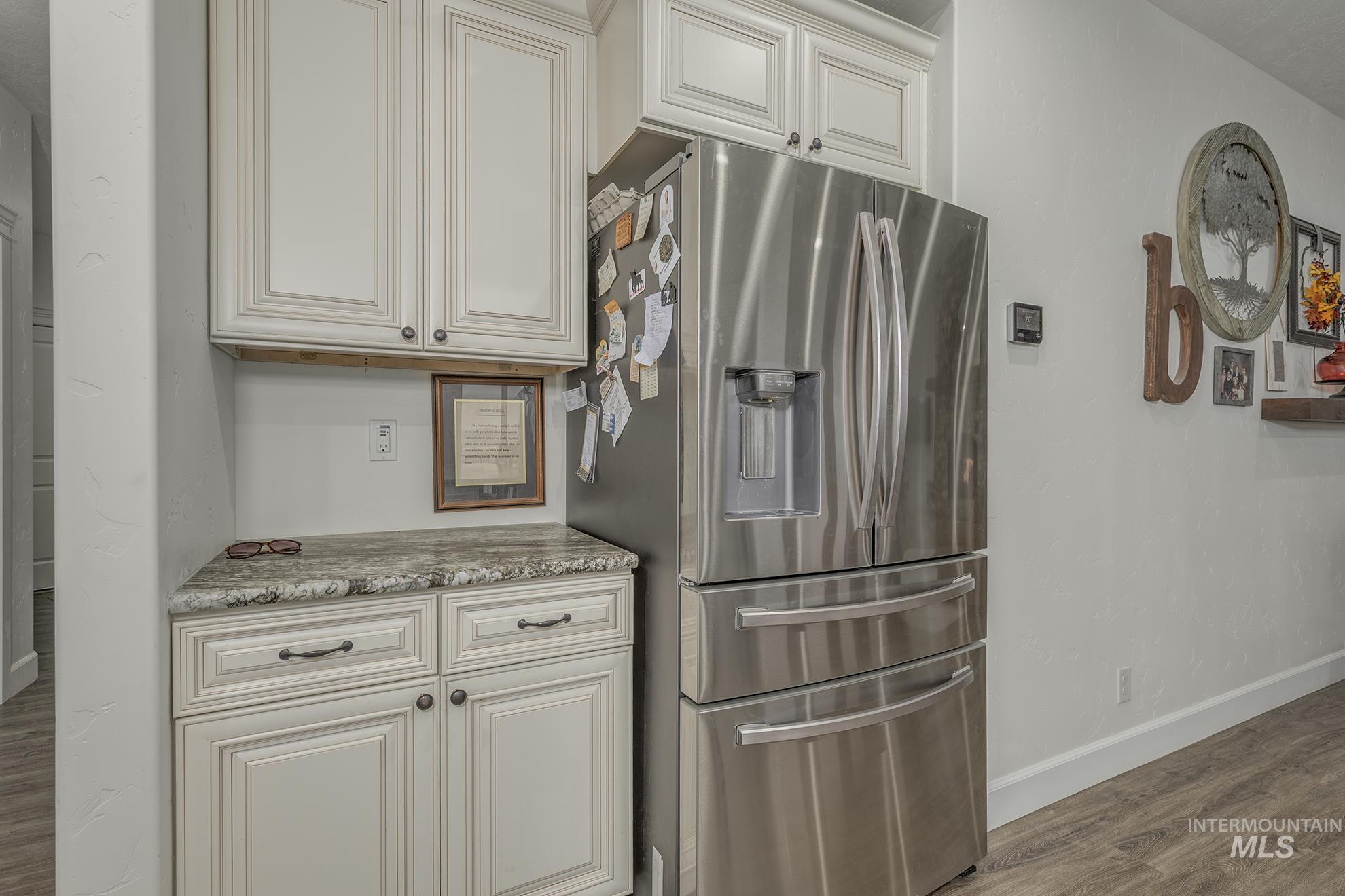 5631 Sunset Road Fruitland, ID 83619 - Photo 14 of 50 Kitchen with stainless steel fridge with ice dispenser, light wood-type flooring, light stone counters, and white cabinets