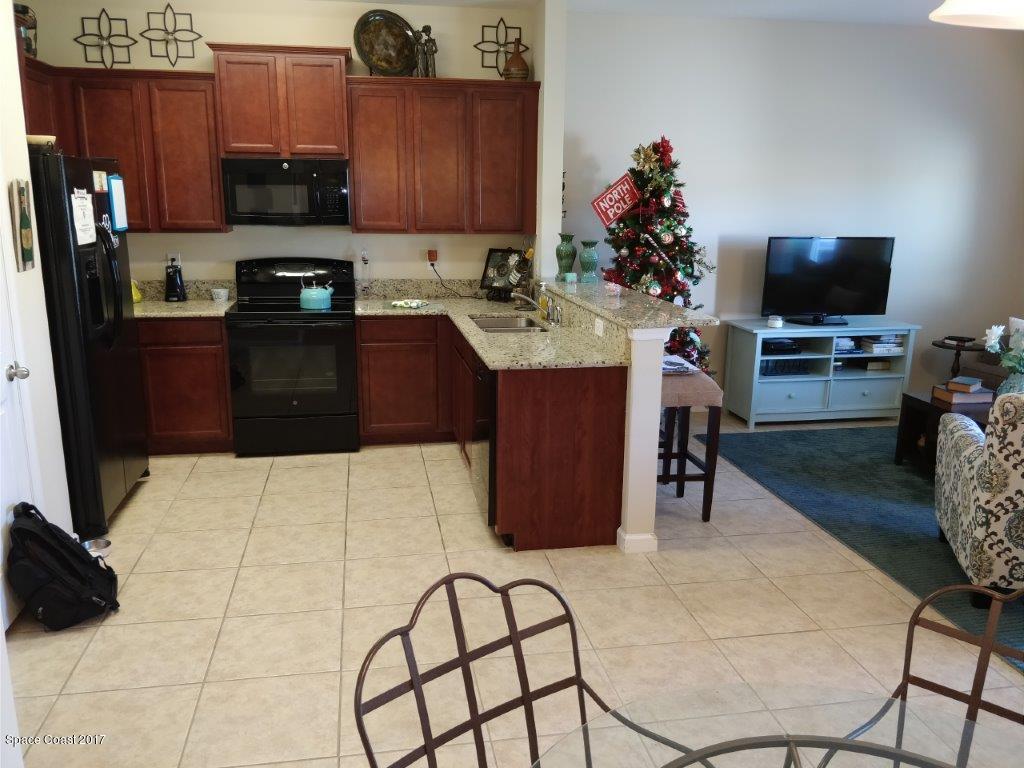 2790 Reston Street, Unit 104 Melbourne, FL 32935 - Photo 11 of 30 a kitchen with stainless steel appliances kitchen island granite countertop a sink a stove and a microwave