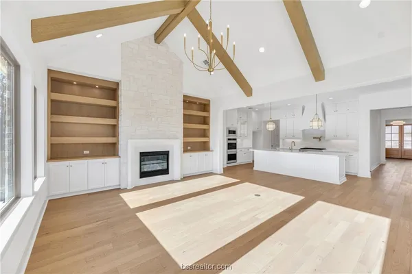 a large white kitchen with kitchen island a sink stainless steel appliances and cabinets