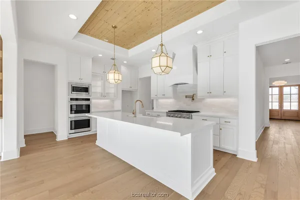 a large room with stainless steel appliances kitchen island a large counter top and a wooden floors