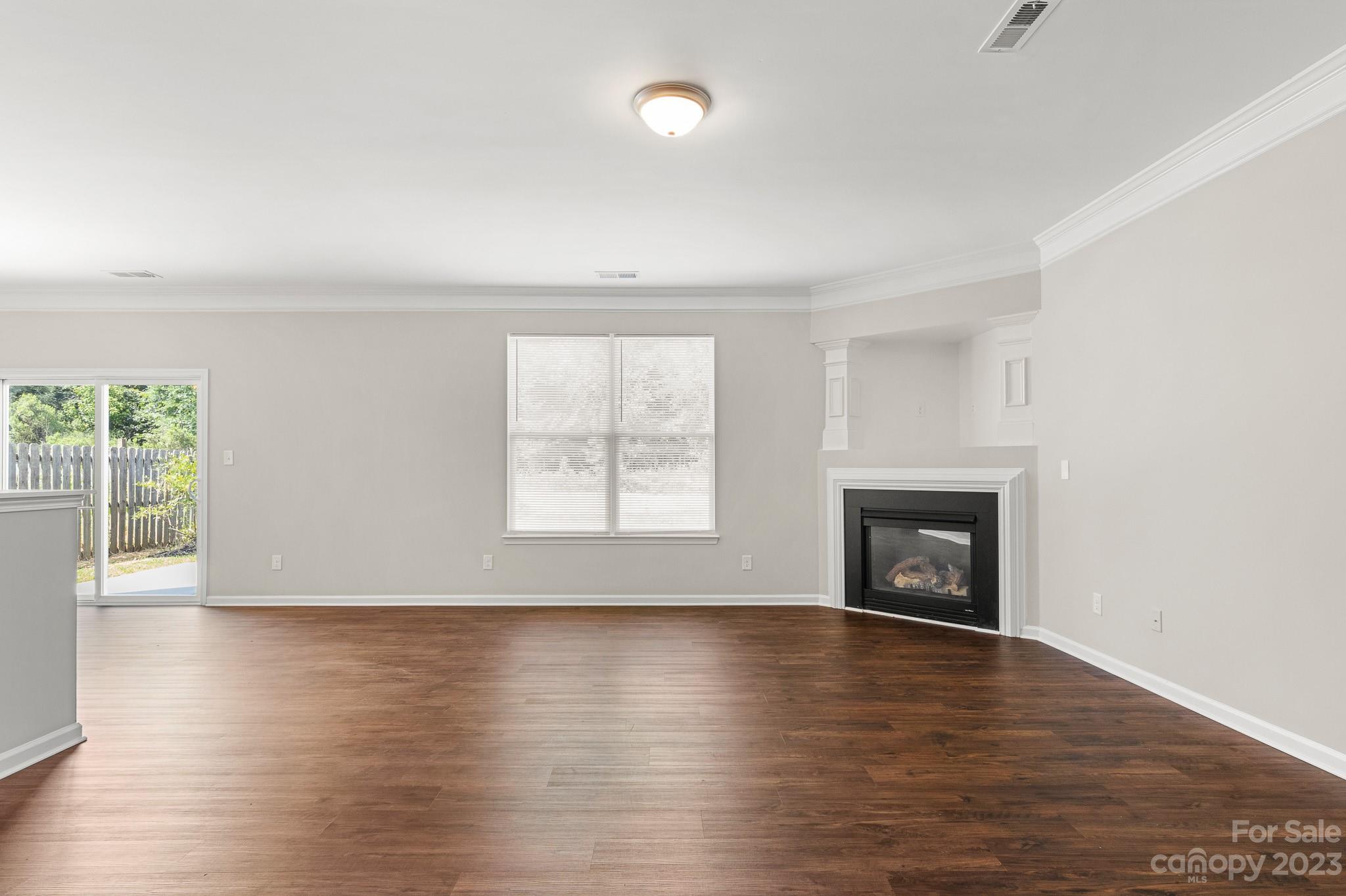 3808 Herkimer Drive Monroe, NC 28110 - Photo 9 of 40 an empty room with wooden floor fireplace and windows