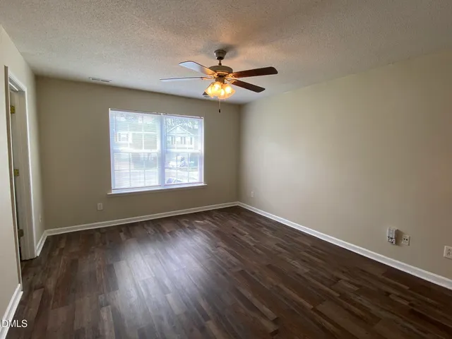 an empty room with wooden floor chandelier fan and windows