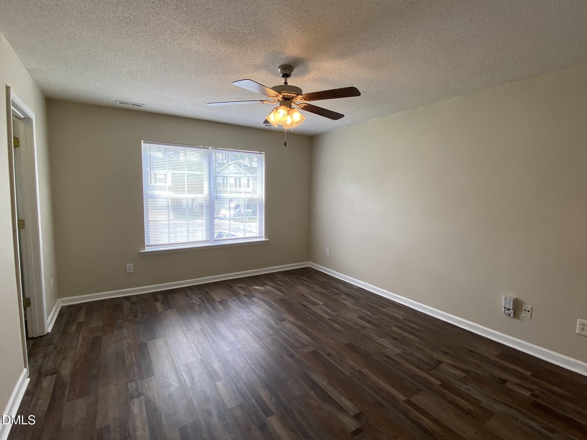 5815 Ricker Road Raleigh, NC 27610 - Photo 17 of 19 an empty room with wooden floor chandelier fan and windows