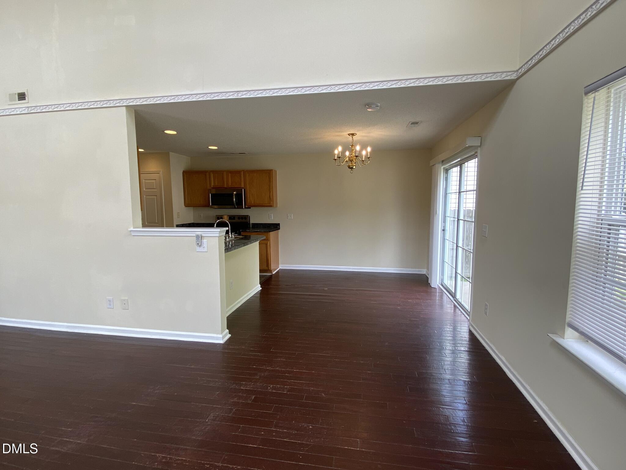 5815 Ricker Road Raleigh, NC 27610 - Photo 5 of 19 an empty room with wooden floor and way to kitchen