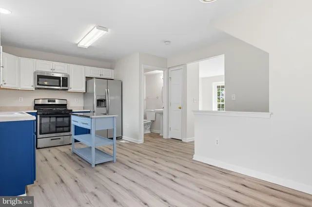 a kitchen with stainless steel appliances granite countertop white cabinets and a stove top oven