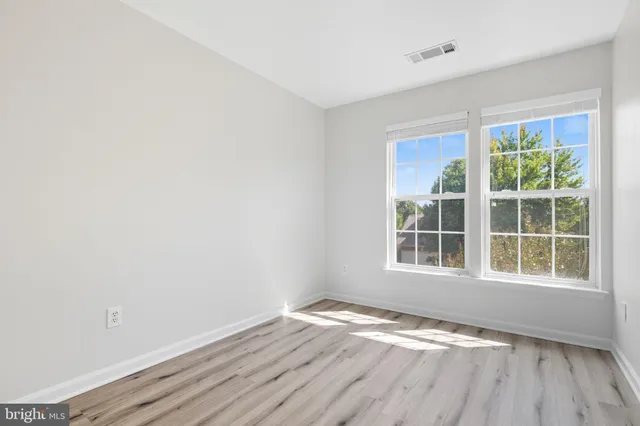 a view of an empty room with closet and wooden floor