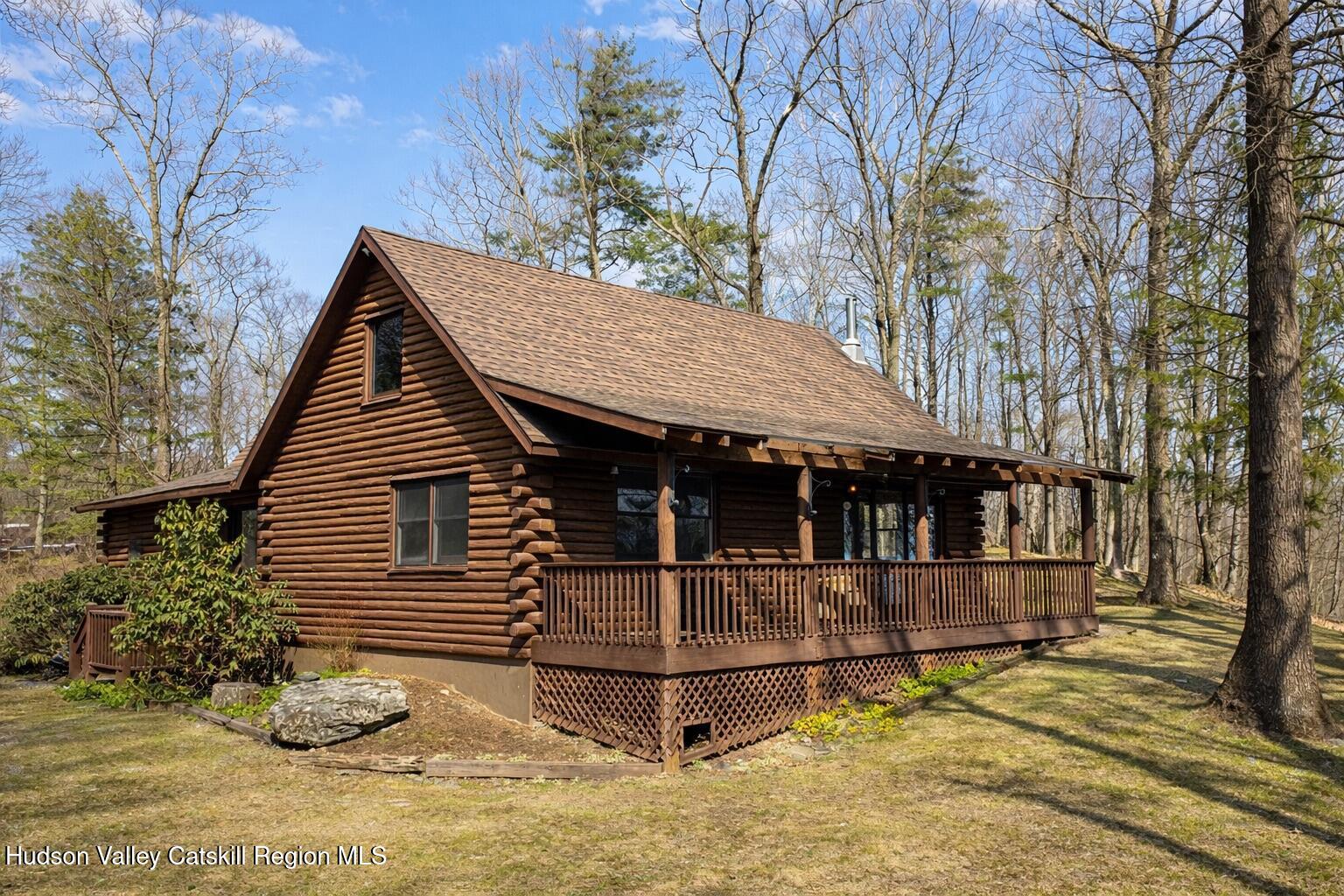 a view of a wooden house with a small yard and large trees