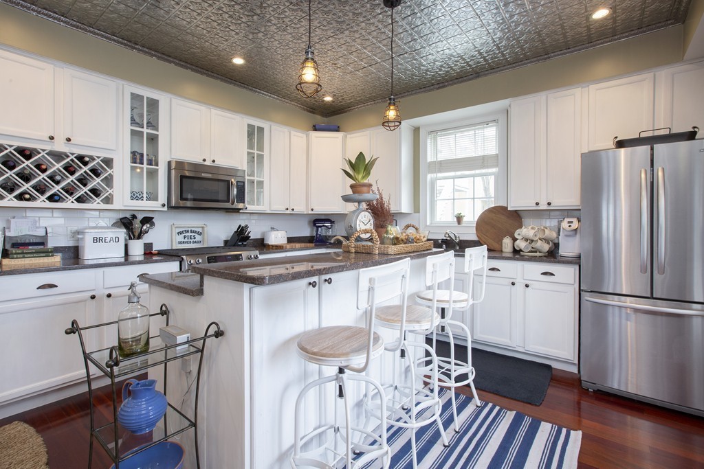 96 Dix Street, Unit 2 Boston, MA 02122 - Photo 2 of 11 a kitchen with stainless steel appliances a refrigerator a stove a sink dishwasher a dining table and chairs with wooden floor
