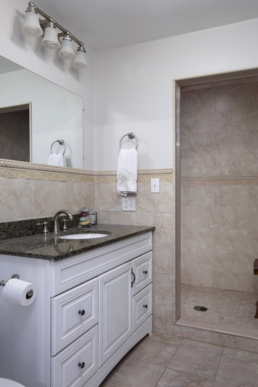 96 Dix Street, Unit 2 Boston, MA 02122 - Photo 7 of 11 a bathroom with a granite countertop sink a mirror and shower