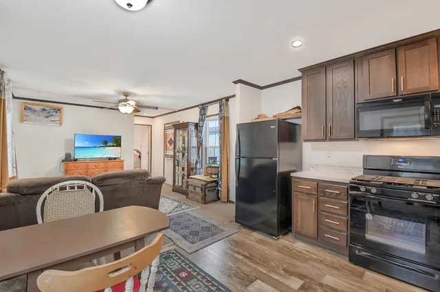 a kitchen with stainless steel appliances granite countertop a refrigerator a stove a sink dishwasher a dining table and chairs with wooden floor