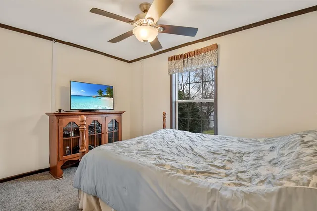 a bedroom with a bed and a flat tv screen on dresser