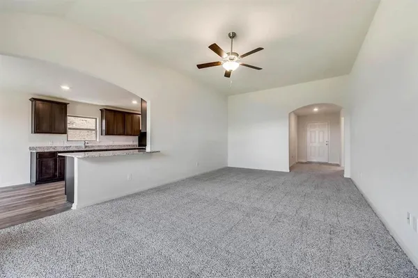 a view of an empty room with a fireplace and a ceiling fan