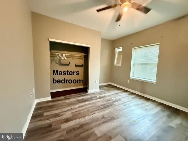 a view of an empty room with window and a ceiling fan