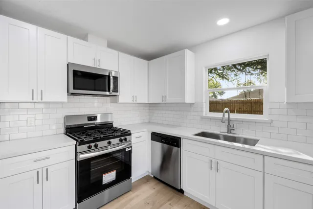 a kitchen with cabinets stainless steel appliances a sink and a window