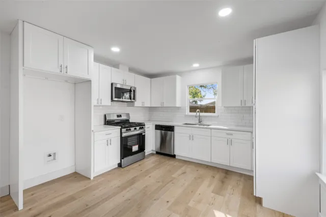 a kitchen with granite countertop white cabinets and stainless steel appliances