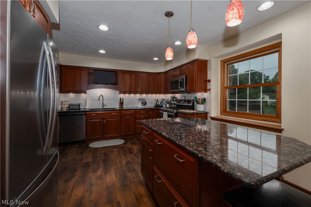 1619 Reed Street Canal Fulton, OH 44614 - Photo 9 of 27 Kitchen featuring recessed lighting and wood-finish flooring, stainless steel appliances, dark cabinetry, and a center island with a granite-style countertop