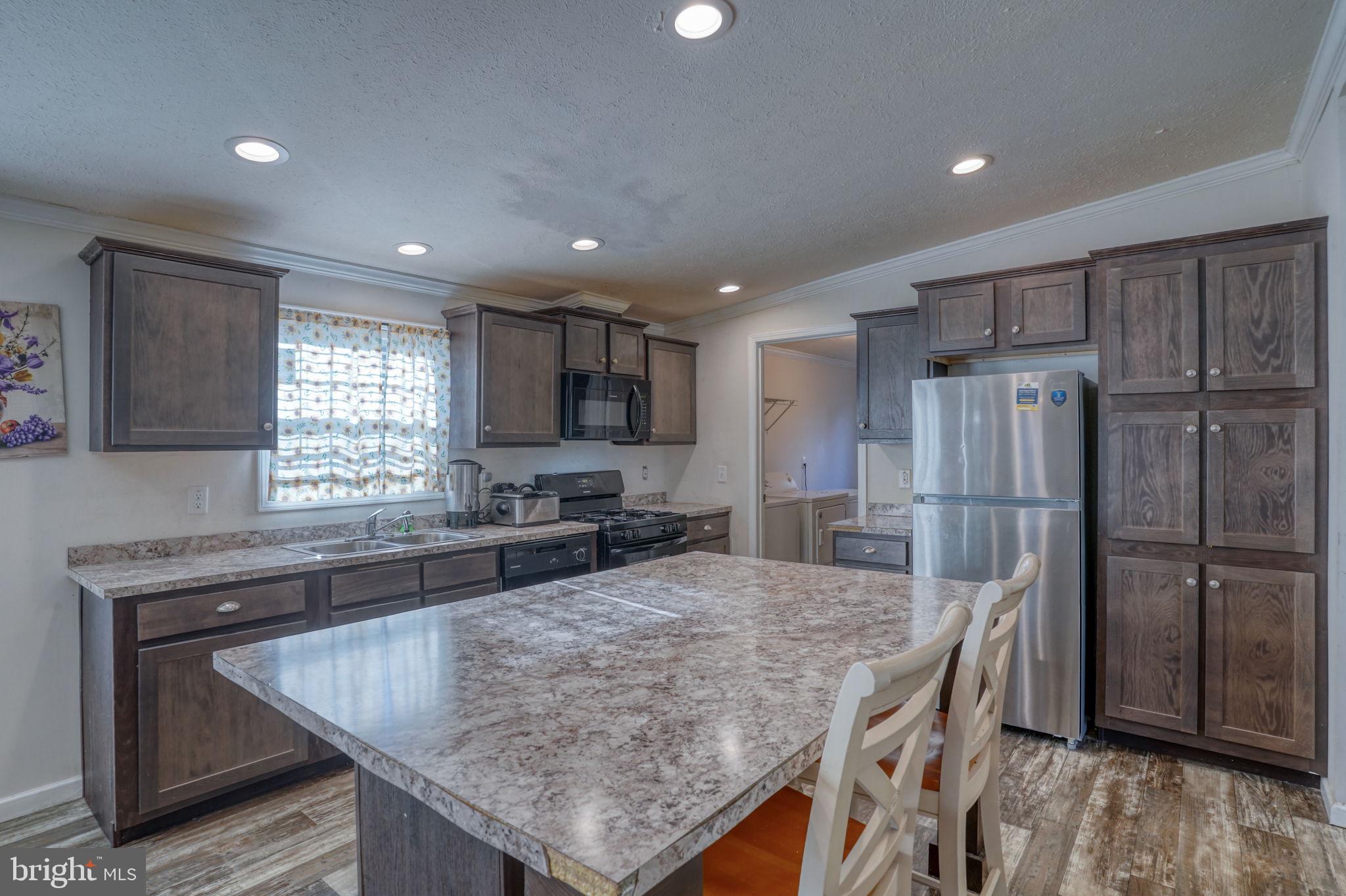 413 4th Street Frederica, DE 19946 - Photo 4 of 31 a kitchen with stainless steel appliances granite countertop a table chairs sink refrigerator and microwave